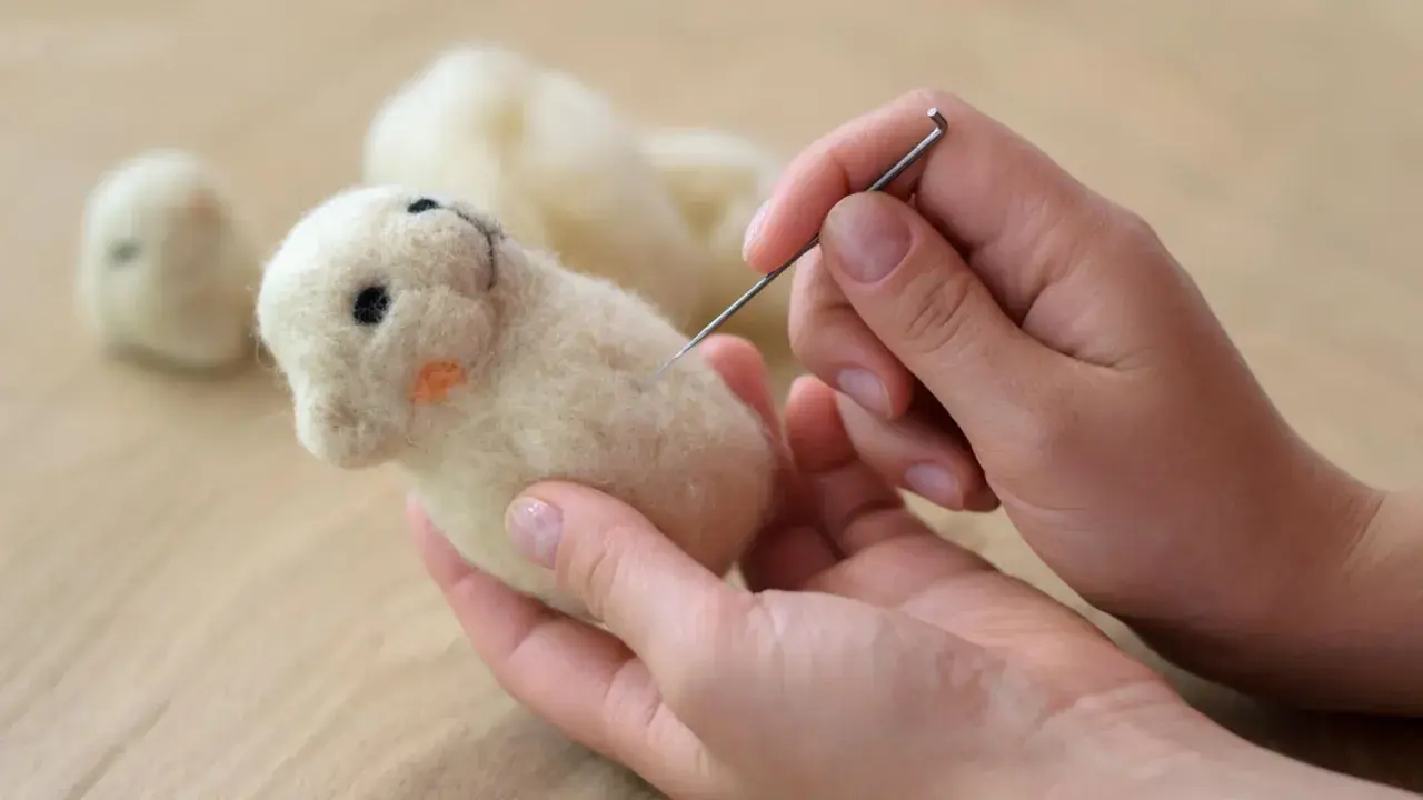 Hände filzen mit Nadel ein süßes Tierchen. Tolle trockenfilzen ideen für kleine Figuren.