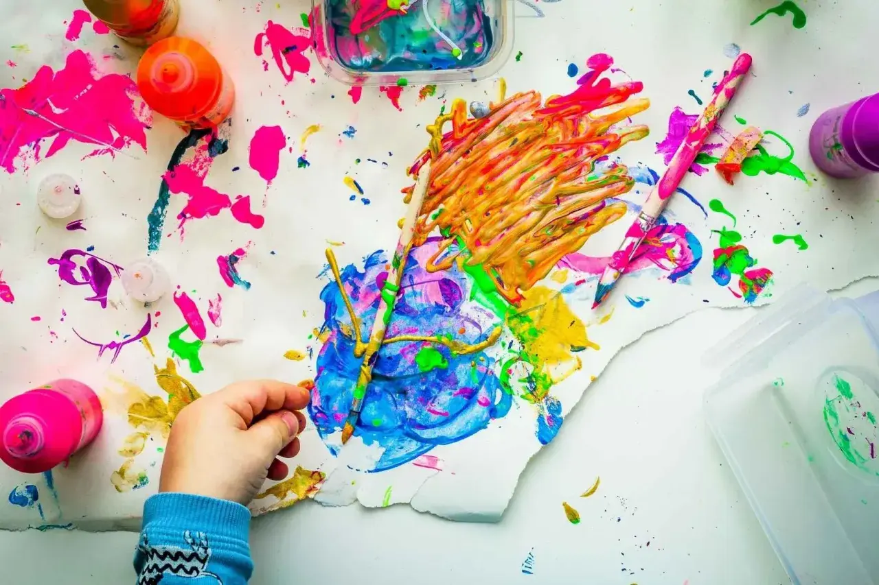 Kreative mal ideen kinder: bunte Farben, Pinsel und ein kleiner Künstler bei der Arbeit.