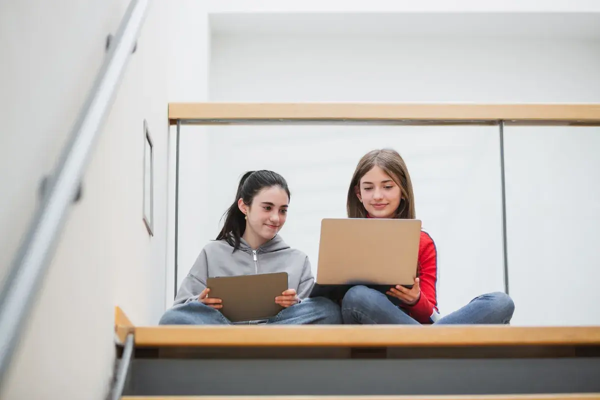 Zwei Mädchen lernen auf Laptops und Tablets. Die Digitalisierung an Schulen Statistik zeigt, wie wichtig diese Geräte für die Bildung sind.