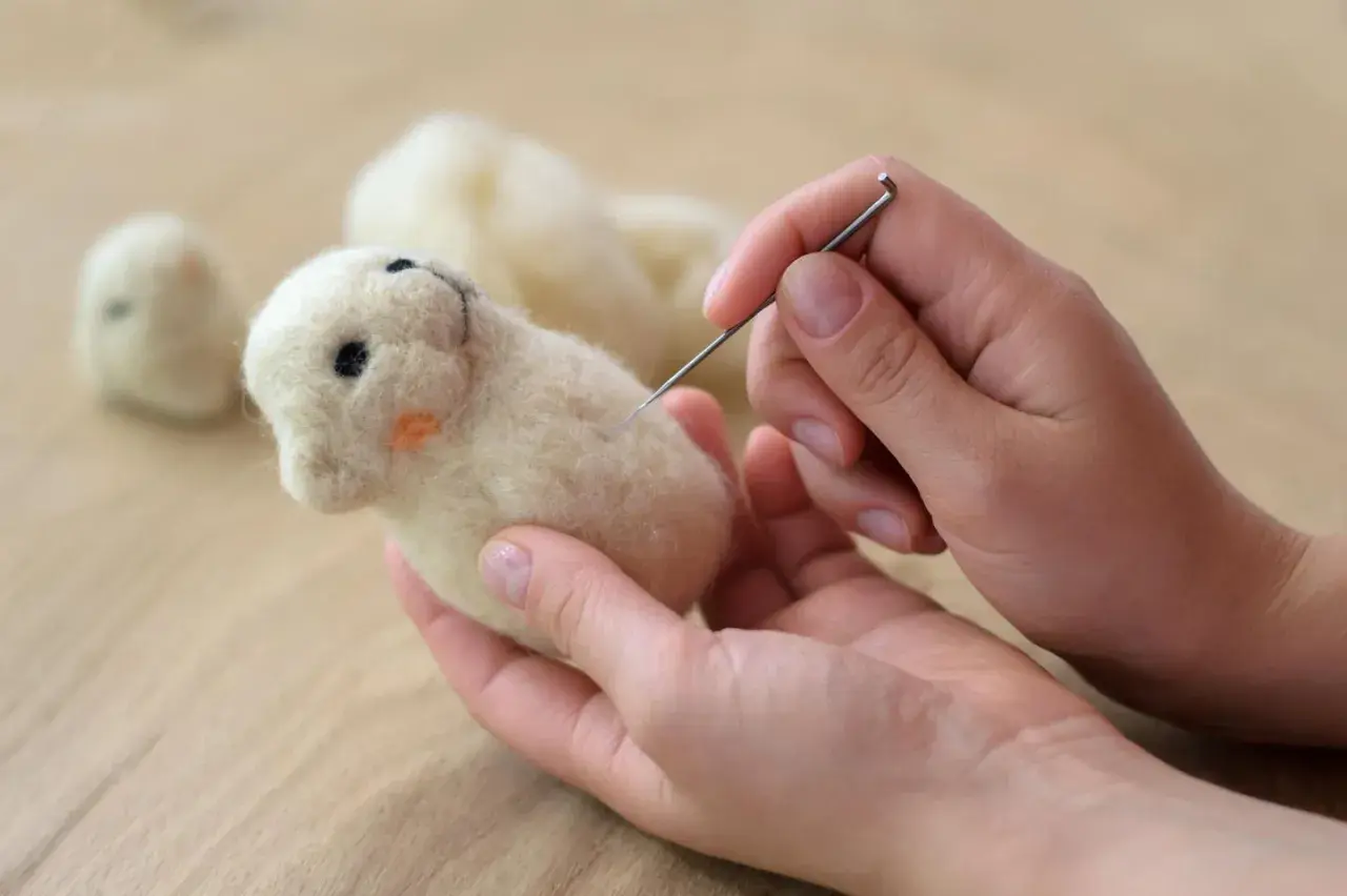 Hände formen mit Nadel und Wolle ein süßes Tierchen. Perfekt für trockenfilzen mit Kindern.