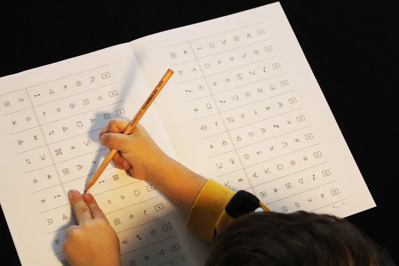 Kind löst einen dyskalkulie test mit Symbolen. Ein Bleistift zeigt auf ein Symbol auf dem Blatt.