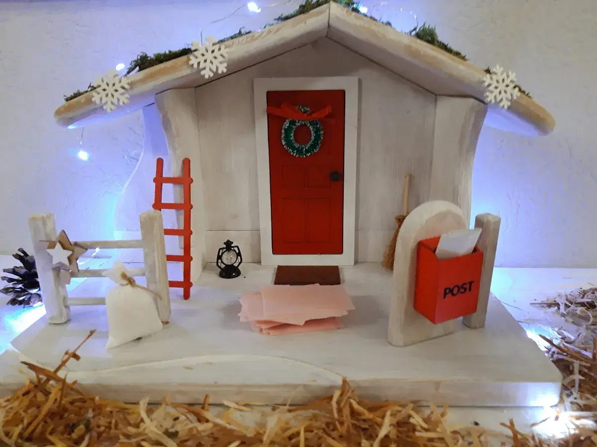 Winterliche Deko mit Weihnachtshaus, Schneeflocken und Lichterkette. Perfekt für Kita-Angebote im Winter.