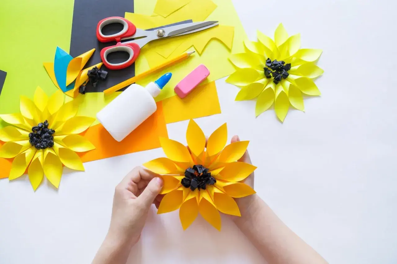 Kinder basteln bunte Papierblumen. Schere, Kleber und Papier liegen bereit für kreative Projekte.