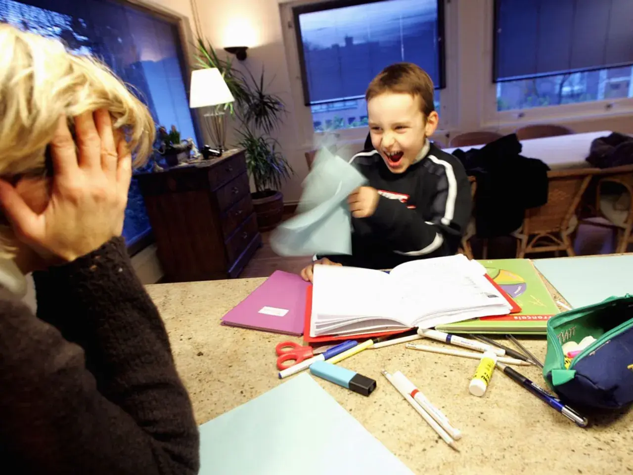 Ein Junge mit ADHS wirft Papier, während seine Mutter verzweifelt die Hände vors Gesicht schlägt.