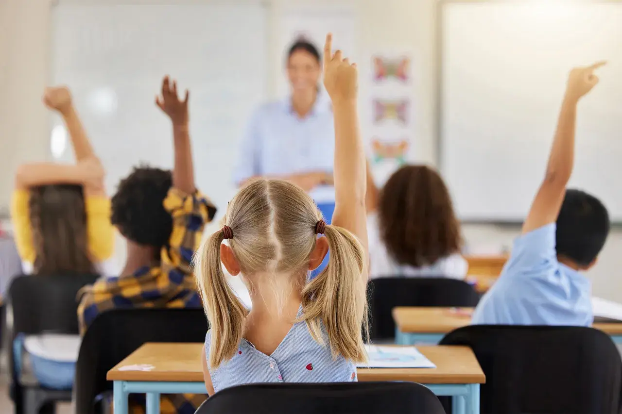Kinder melden sich im Unterricht, um Fragen zu beantworten. Ein guter Start in der neuen Schule!