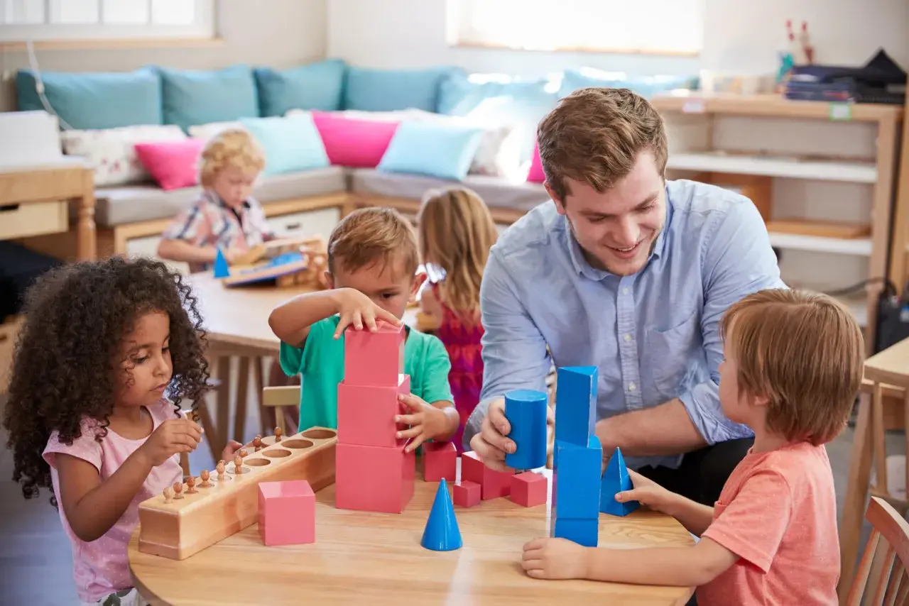 Lehrer fördert mathematische Bildung in der Kita durch spielerisches Bauen mit geometrischen Formen.
