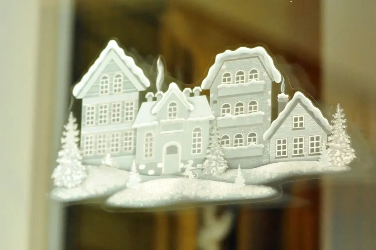 Winterliche Häuser mit Schnee bedeckt, ein Beispiel für schöne Fensterbilder basteln.