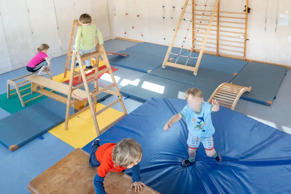 Kinder erkunden eine Turnhalle mit Kletterger&uuml;st, Sprossenwand und Matten. Tolle Ideen f&uuml;r eine Kindergarten-Turnhalle!
