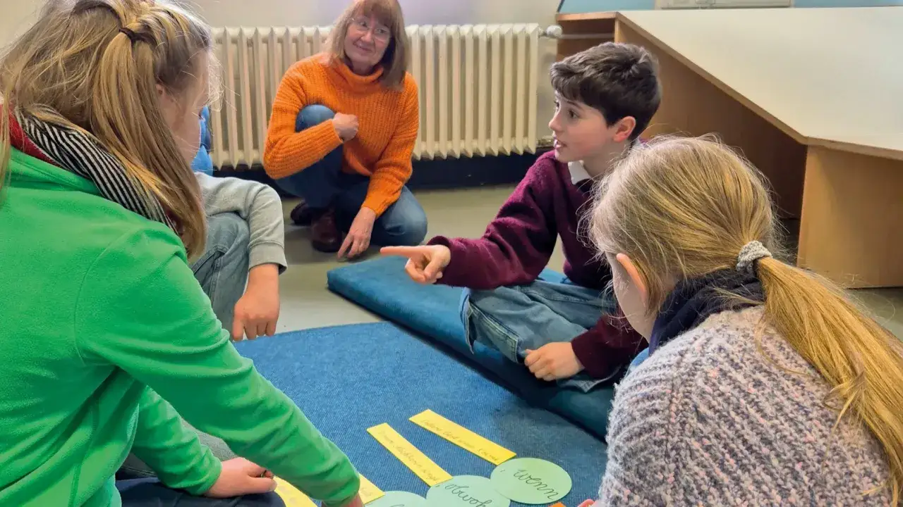 Kinder diskutieren, was bedeutet haltung, während eine Lehrerin zusieht.