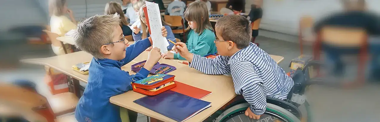 Zwei Jungen lernen gemeinsam, einer im Rollstuhl. Ein Beispiel f&uuml;r gelungene Inklusion an Schulen, wo jeder dazugeh&ouml;rt und unterst&uuml;tzt wird.