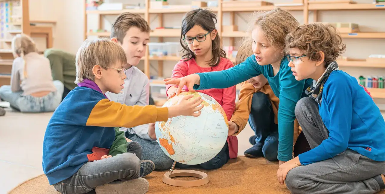 Kinder erkunden gemeinsam einen Globus. Dies ist ein Beispiel für Inklusion, wo alle gleichberechtigt lernen und teilhaben.