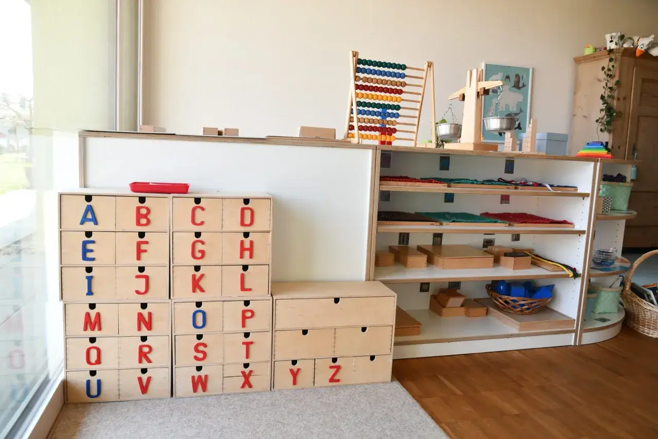 Holzm&ouml;bel mit Buchstaben-Schubladen und Lernmaterialien in einem Montessori Kindergarten.